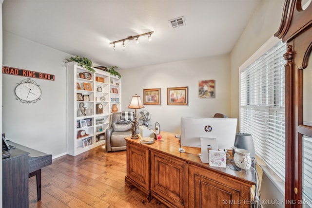 office space with rail lighting and light hardwood / wood-style flooring