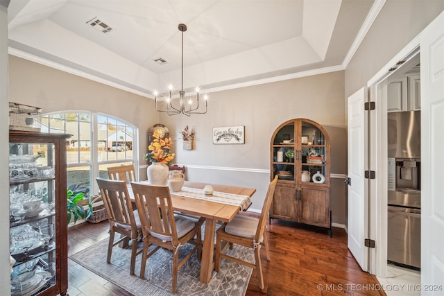 dining area with dark hardwood / wood-style flooring, a raised ceiling, a notable chandelier, and crown molding