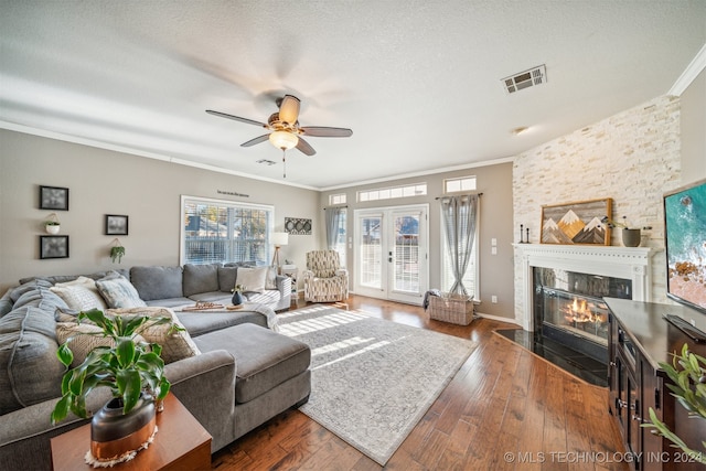 living room featuring a stone fireplace, ceiling fan, dark hardwood / wood-style flooring, and ornamental molding