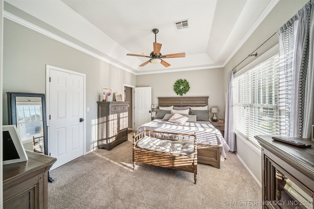 bedroom with ceiling fan, a raised ceiling, ornamental molding, and light carpet