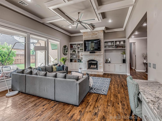 living room with ceiling fan, coffered ceiling, a stone fireplace, dark hardwood / wood-style floors, and ornamental molding