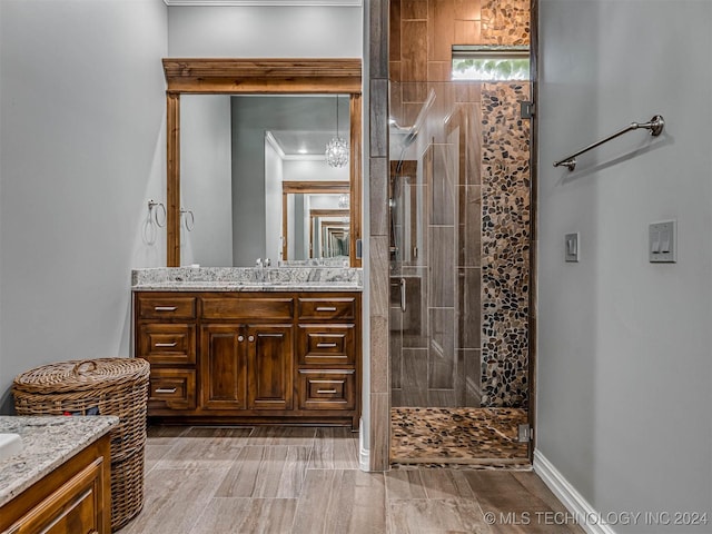 bathroom featuring a tile shower, vanity, and ornamental molding