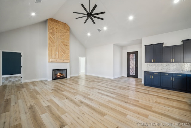 unfurnished living room featuring high vaulted ceiling, a glass covered fireplace, ceiling fan, and light wood finished floors