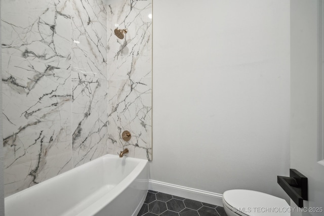 bathroom featuring tile patterned flooring, tub / shower combination, toilet, and baseboards