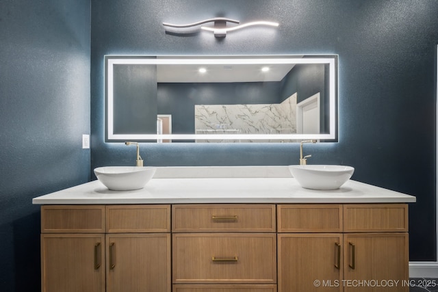 bathroom featuring a textured wall, a sink, and double vanity