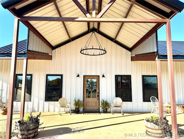 view of exterior entry featuring board and batten siding and a patio