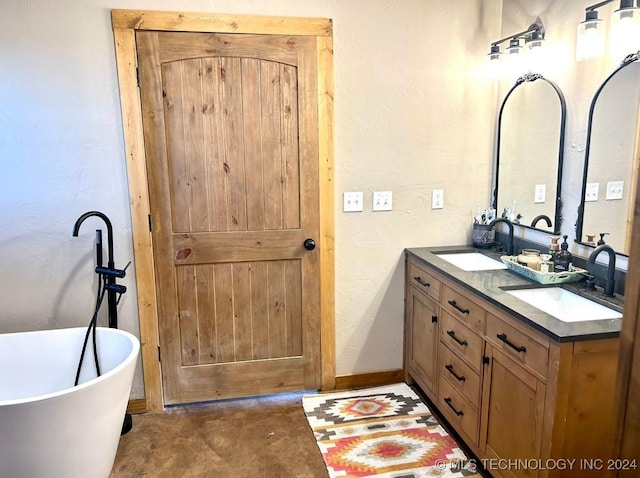 bathroom featuring a textured wall, a freestanding tub, a sink, and double vanity