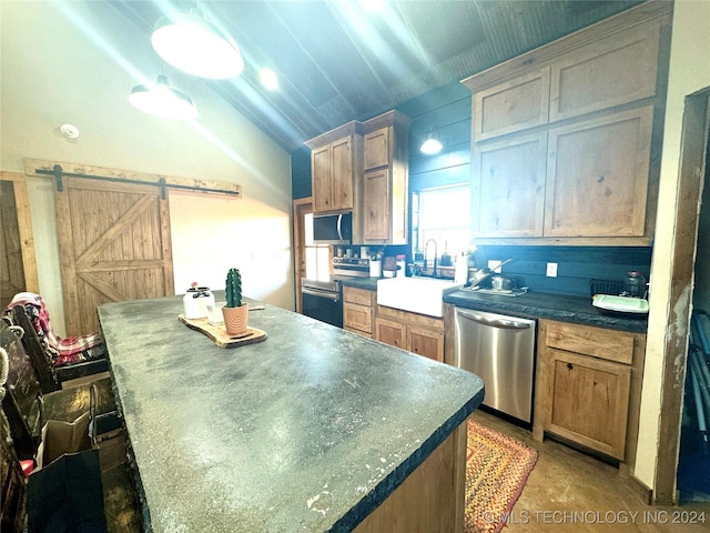 kitchen featuring lofted ceiling, dark countertops, appliances with stainless steel finishes, a sink, and a kitchen island