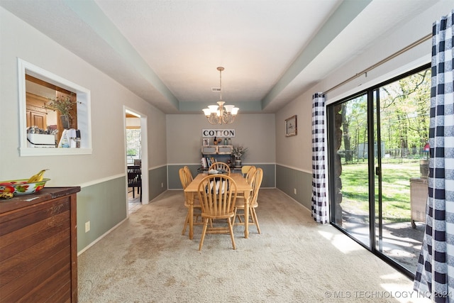 dining area featuring a raised ceiling, light colored carpet, and a chandelier