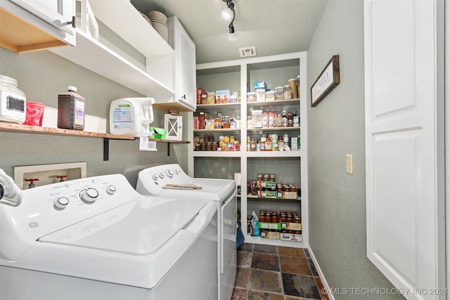 clothes washing area with washer and dryer, cabinets, and a textured ceiling