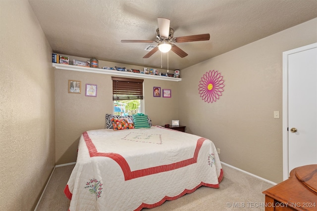 bedroom with ceiling fan, carpet floors, and a textured ceiling