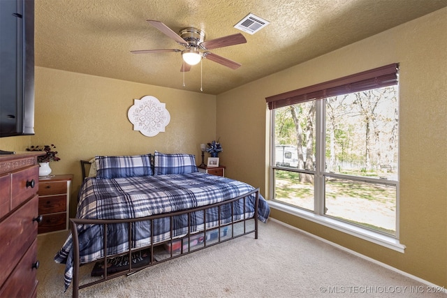 bedroom featuring ceiling fan, carpet floors, and a textured ceiling