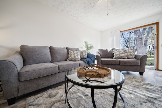 living room featuring a textured ceiling, vaulted ceiling, and ceiling fan