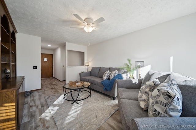 living room with ceiling fan, light hardwood / wood-style floors, and a textured ceiling