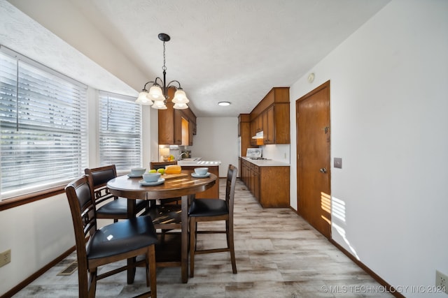 dining area with light hardwood / wood-style floors, a textured ceiling, and an inviting chandelier