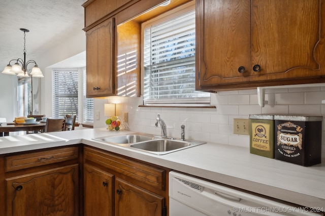 kitchen with white dishwasher, plenty of natural light, sink, and decorative light fixtures