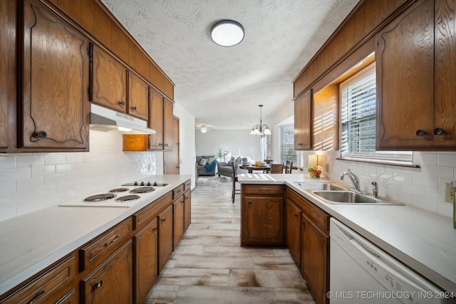 kitchen with white appliances, sink, hanging light fixtures, light wood-type flooring, and a textured ceiling