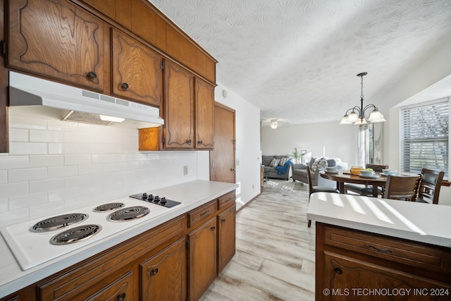 kitchen with light hardwood / wood-style flooring, a notable chandelier, decorative light fixtures, a textured ceiling, and white electric stovetop