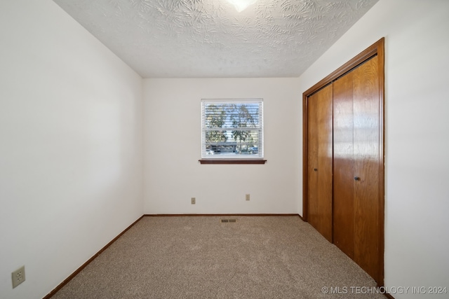 unfurnished bedroom featuring carpet flooring, a textured ceiling, and a closet