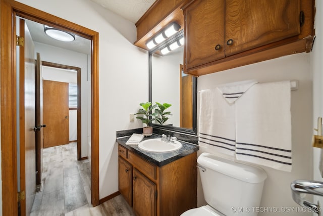 bathroom with wood-type flooring, vanity, and toilet