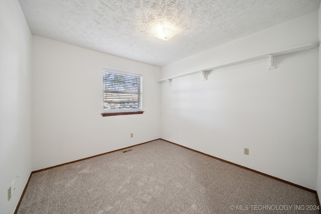 spare room with carpet and a textured ceiling