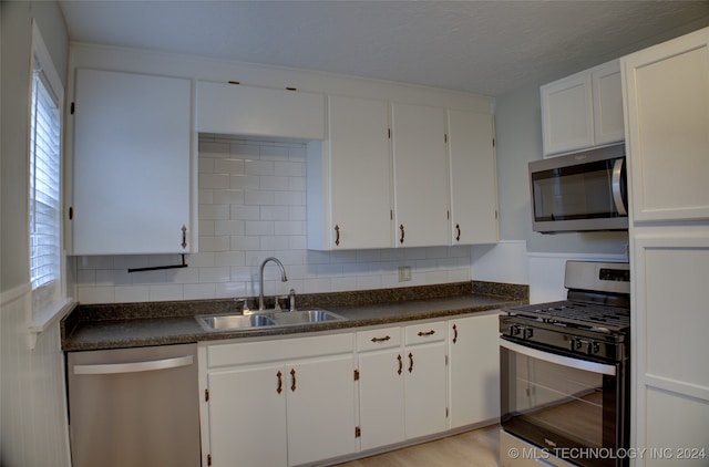 kitchen featuring white cabinetry, sink, stainless steel appliances, light hardwood / wood-style floors, and decorative backsplash