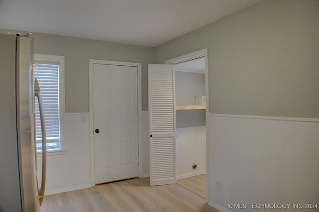 unfurnished bedroom featuring stainless steel fridge, light wood-type flooring, and multiple windows