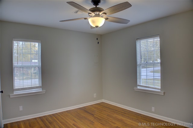 empty room featuring wood-type flooring, ceiling fan, and a healthy amount of sunlight