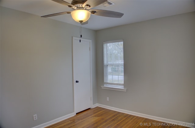 empty room with ceiling fan, plenty of natural light, and wood-type flooring