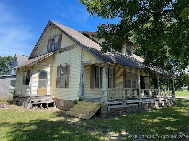 back of house with covered porch and a lawn