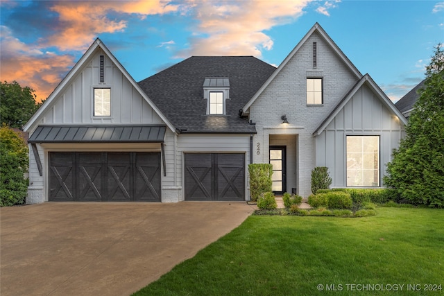 modern inspired farmhouse featuring a garage and a lawn