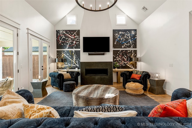 living room featuring high vaulted ceiling, light hardwood / wood-style floors, and an inviting chandelier