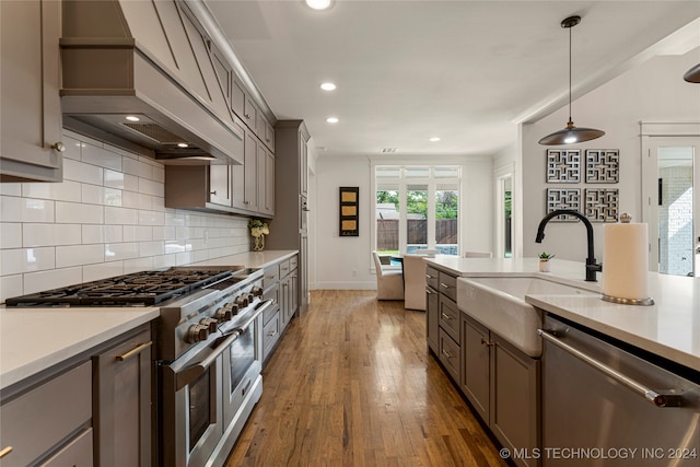 kitchen with custom exhaust hood, stainless steel appliances, dark wood-type flooring, sink, and pendant lighting