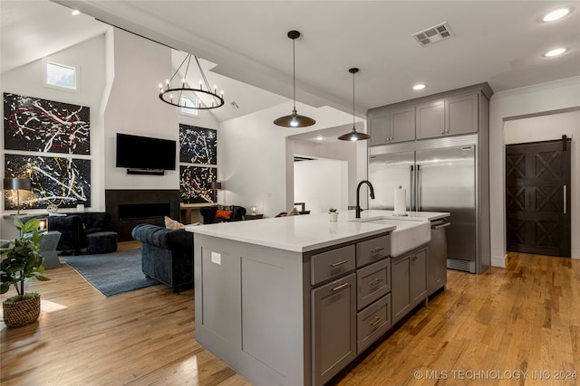 kitchen with a center island with sink, gray cabinets, light hardwood / wood-style floors, and hanging light fixtures