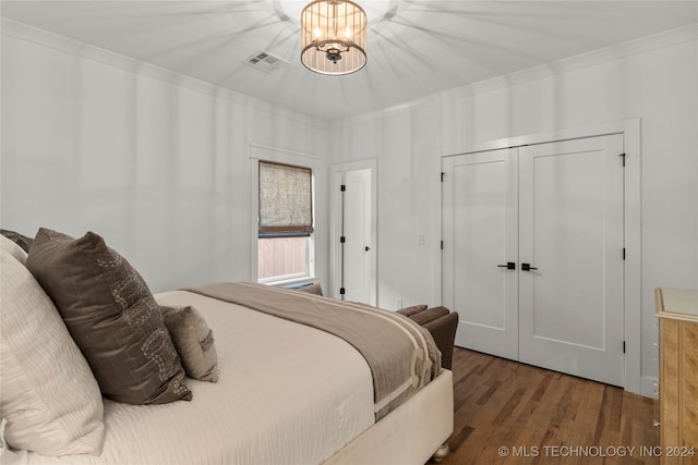 bedroom featuring a chandelier, dark hardwood / wood-style flooring, a closet, and ornamental molding