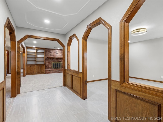 hallway featuring built in shelves and light colored carpet