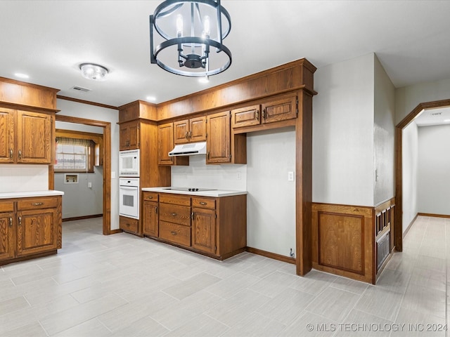 kitchen with ornamental molding, hanging light fixtures, white appliances, and an inviting chandelier