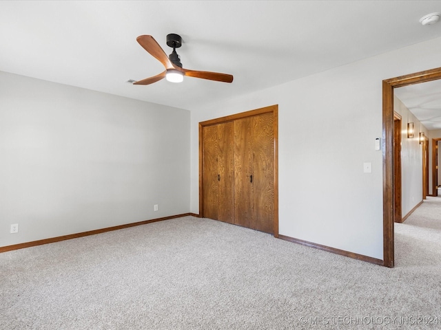 unfurnished bedroom with light carpet, a closet, and ceiling fan