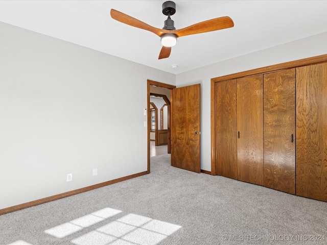 unfurnished bedroom featuring light carpet, a closet, and ceiling fan