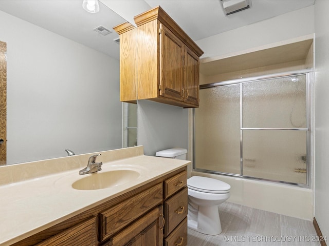 full bathroom featuring vanity, toilet, and bath / shower combo with glass door