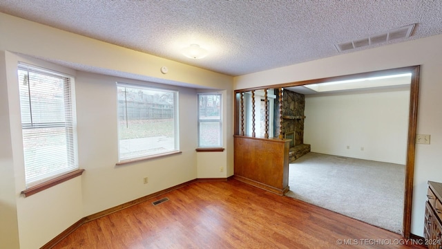 unfurnished room with a textured ceiling and light hardwood / wood-style flooring