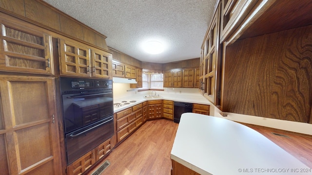 kitchen featuring light wood-type flooring, a textured ceiling, white gas cooktop, sink, and black dishwasher