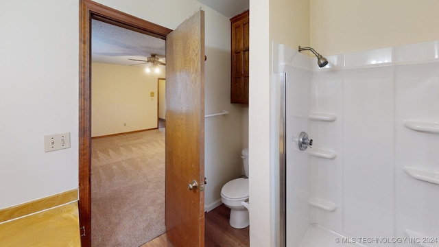 bathroom with hardwood / wood-style flooring, ceiling fan, toilet, and a shower with shower door