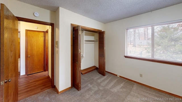 unfurnished bedroom with light colored carpet, a textured ceiling, and a closet