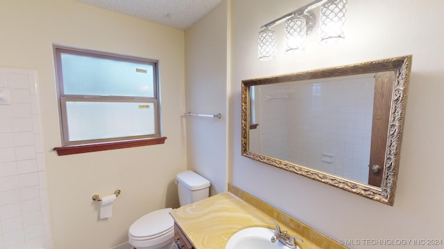 bathroom with vanity, toilet, and a textured ceiling