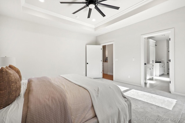 bedroom with ceiling fan, a raised ceiling, and ensuite bath