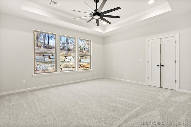 carpeted spare room featuring ceiling fan and a raised ceiling