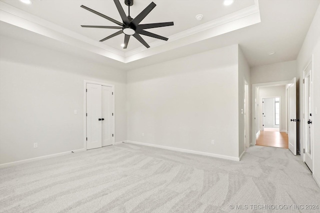 carpeted empty room featuring ceiling fan, ornamental molding, and a tray ceiling