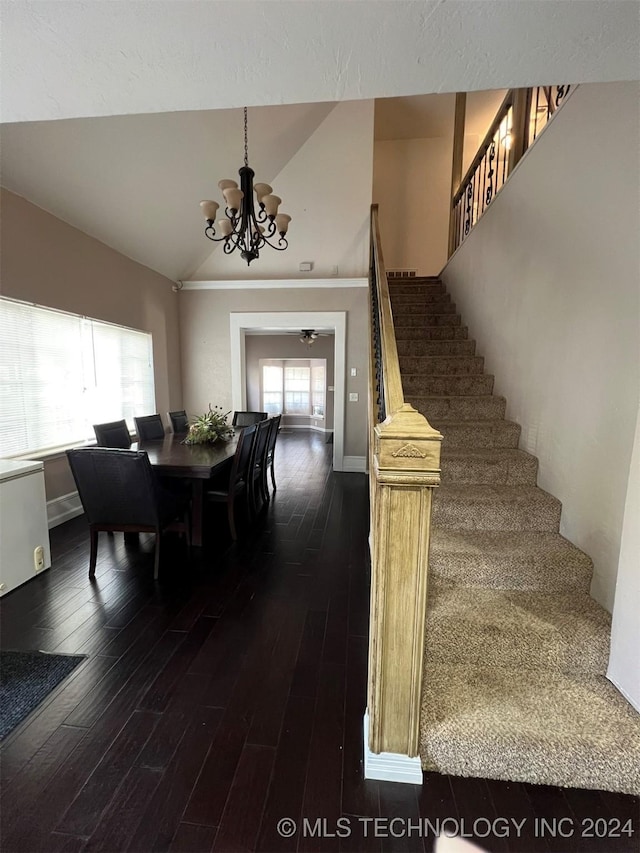 dining space with ceiling fan with notable chandelier, dark hardwood / wood-style flooring, and lofted ceiling