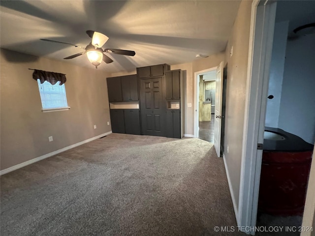 interior space featuring stainless steel fridge, ceiling fan, and dark colored carpet